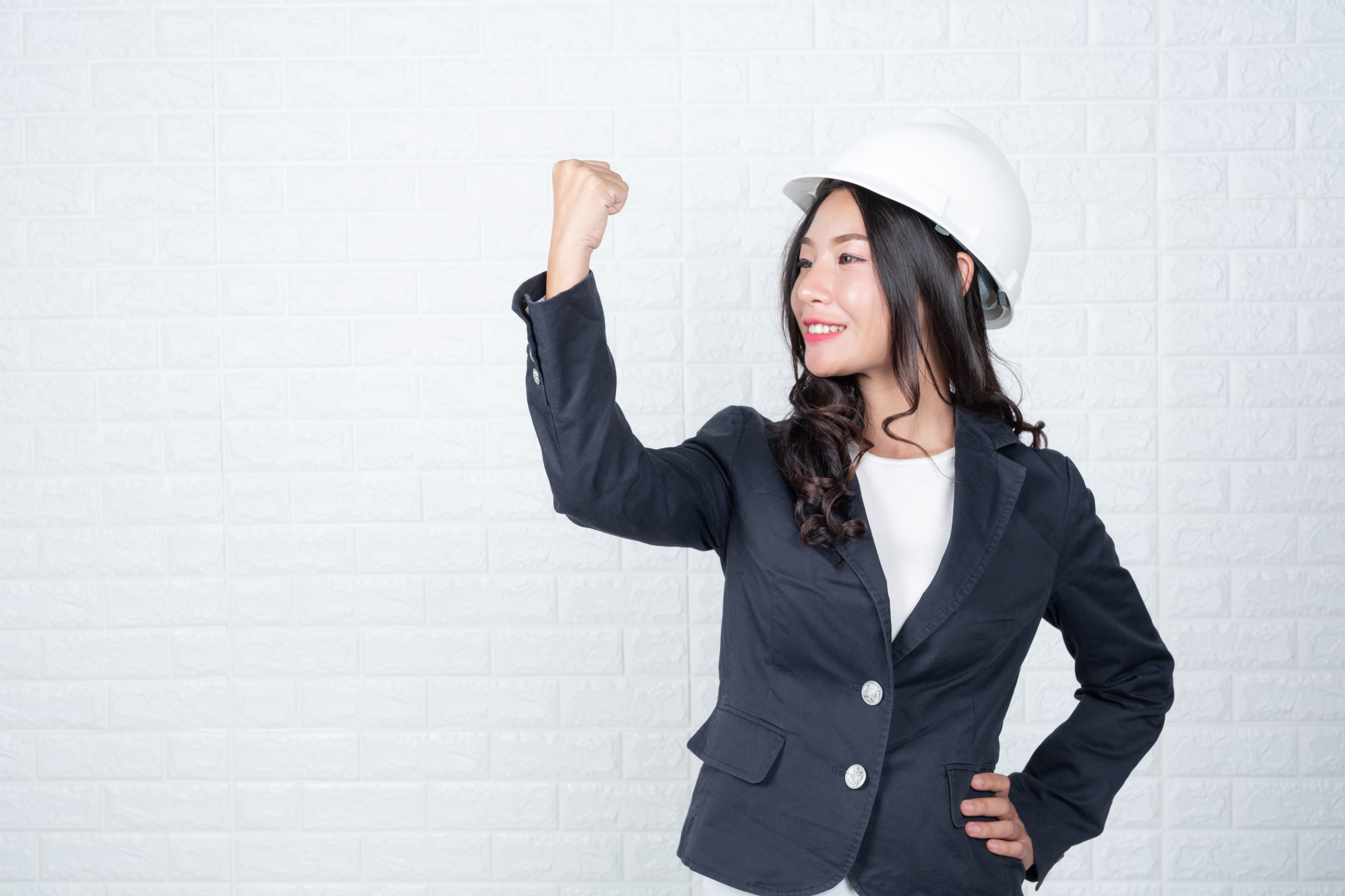 woman-engineering-holding-hat-separate-white-brick-wall-made-gestures-with-sign-language
